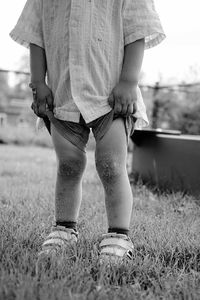 Low section of woman standing on grassy field