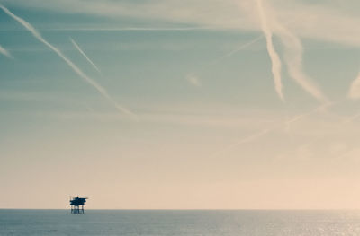 Scenic view of sea against vapor trails in sky