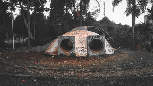 Old abandoned building on field against trees in forest
