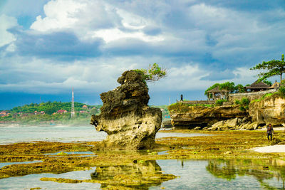 Rock formation on beach against sky