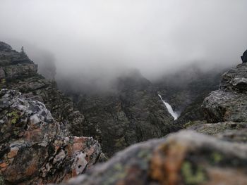 Scenic view of rocky mountains in foggy weather