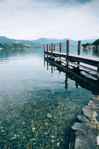 Wooden posts in lake against sky