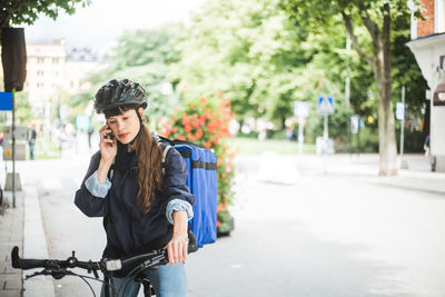 Young woman using phone while standing on street in city