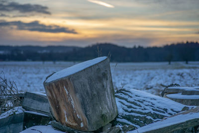 Snow on land against sky during sunset