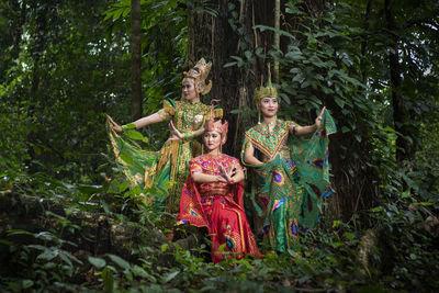 Friends wearing traditional clothing standing amidst plants in forest