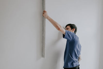Caucasian plasterer man checks the evenness of the walls after puttying.