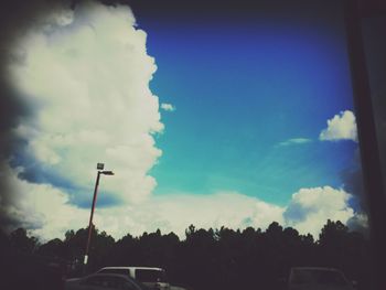 View of cars on road against cloudy sky