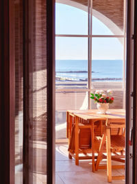 Chairs and table by sea seen through window