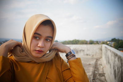 Portrait of beautiful young woman standing against sky