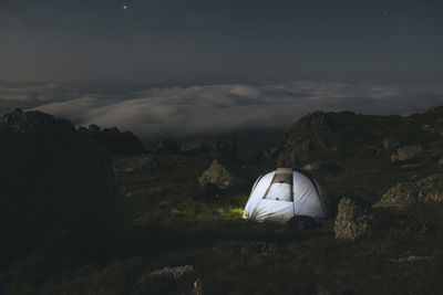 Tent on rocky mountain against sky