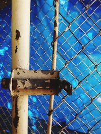 Low angle view of chainlink fence against blue sky