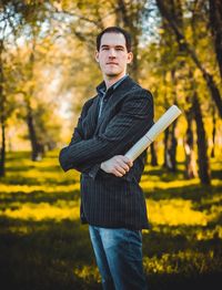 Confident businessman standing with document at park