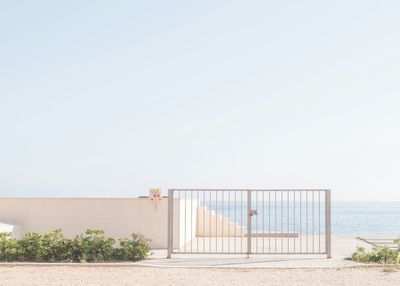 Gate on sea shore against clear sky