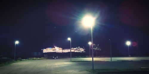 Illuminated street against sky at night