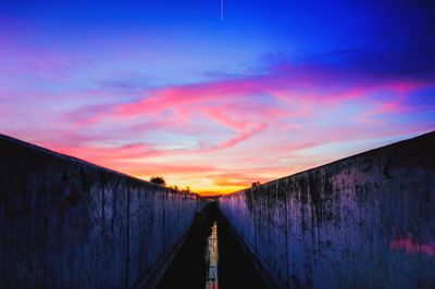 Footbridge against sky during sunset