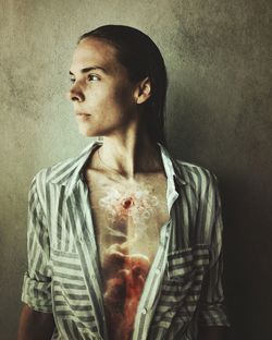 Portrait of young woman standing against gray background