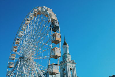 Low angle view of ferris wheel against clear blue sky