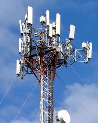 Low angle view of communications tower against blue sky