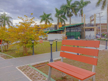 Bench by building against sky during autumn