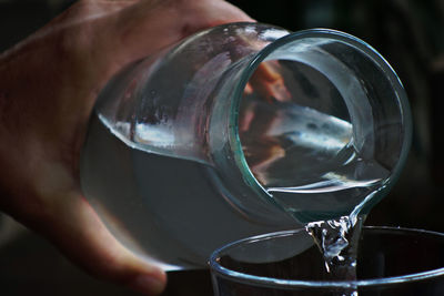 Cropped image of person pouring water in drinking glass