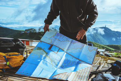 Man holding umbrella against mountains