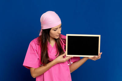 Woman holding pink while standing against blue background