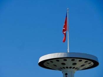 Low angle view of flag on tower against blue sky