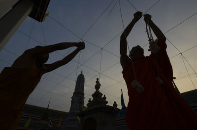 Low angle view of silhouette people decorating temple