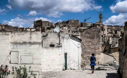 Rear view of man walking on old building against sky