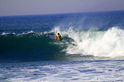 Man surfing in sea against sky