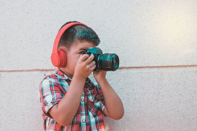 Boy photographing against wall