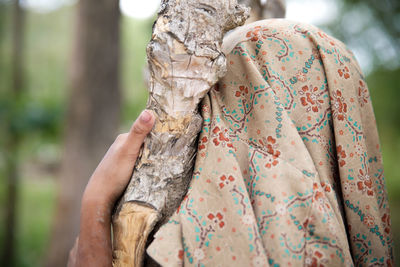 Person with covered face touching dry plant