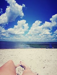 Low section of person on beach against sky