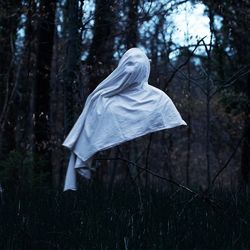 White ghost against trees in forest