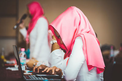 Side view of woman using smart phone on laptop at auditorium