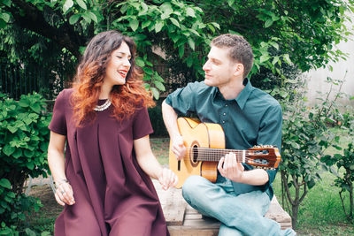 Woman singing while man playing guitar in park