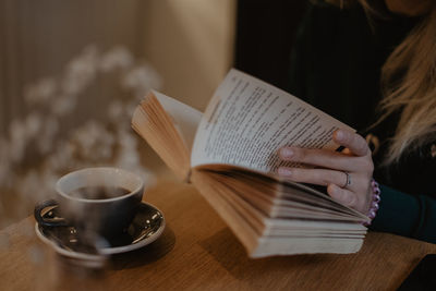 Midsection of woman holding coffee cup on table