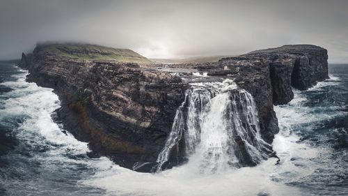 Panoramic view of waterfall by sea against sky