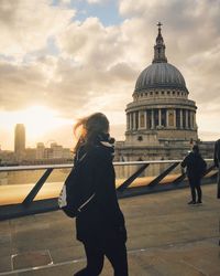 Man standing in front of cityscape against cloudy sky