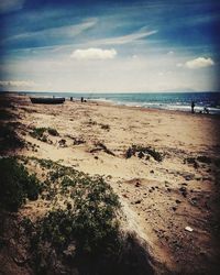 Scenic view of beach against cloudy sky