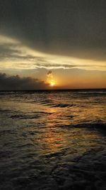 Scenic view of sea against dramatic sky during sunset