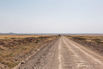 Road amidst field against clear sky