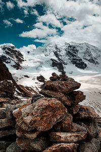 Stack of rocks on snowcapped mountain against sky