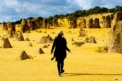 Full length rear view of woman walking in desert