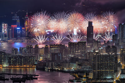 Firework display over illuminated buildings in city at night