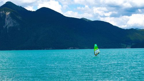 Mid distance of person windsurfing on sea by mountains