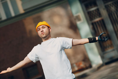 Young man holding yellow while standing against built structure