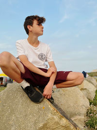 Portrait of young man sitting on rock at beach