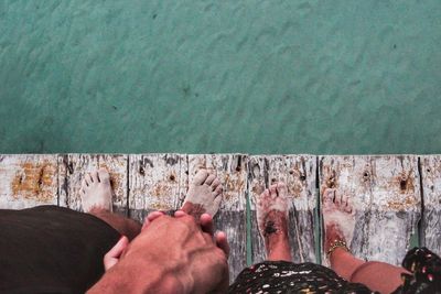 Low section of couple standing on pier by sea