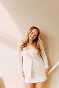 Happy cheerful emotional young woman with long blonde hair posing on a solid background